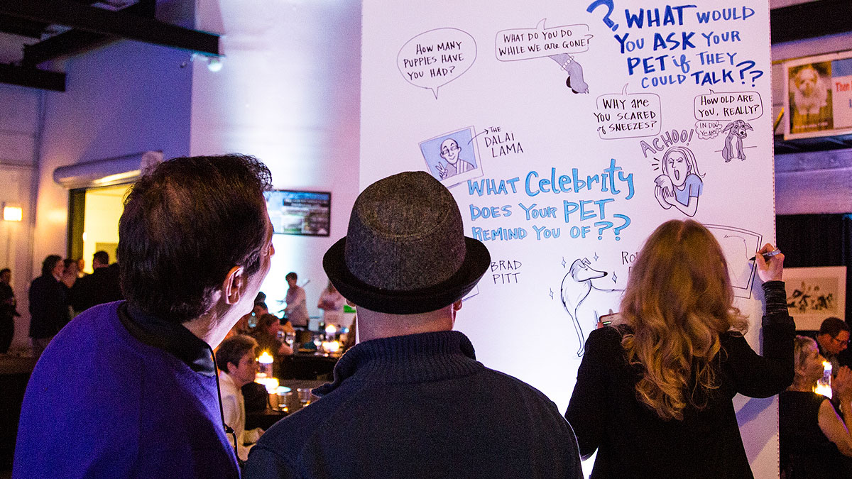 Attendees watch Ink Factory artists create visual notes for the Puppy mill Project