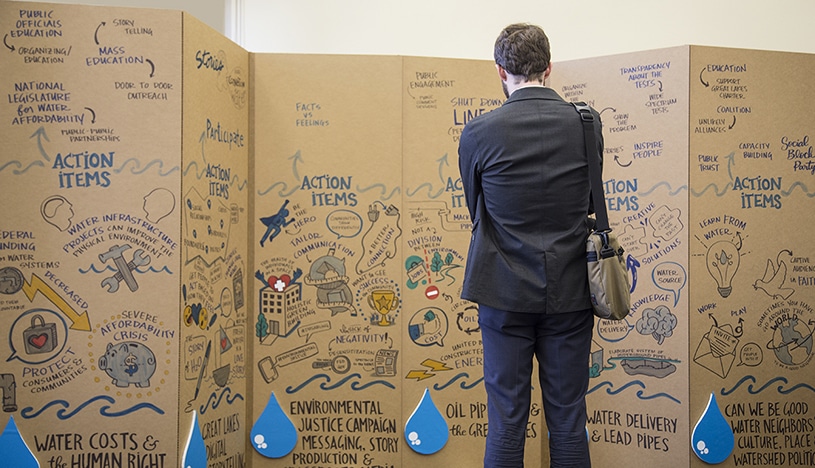 An attendee to the Freshwater Lab summit in Chicago studies a mural created by Ink Factory