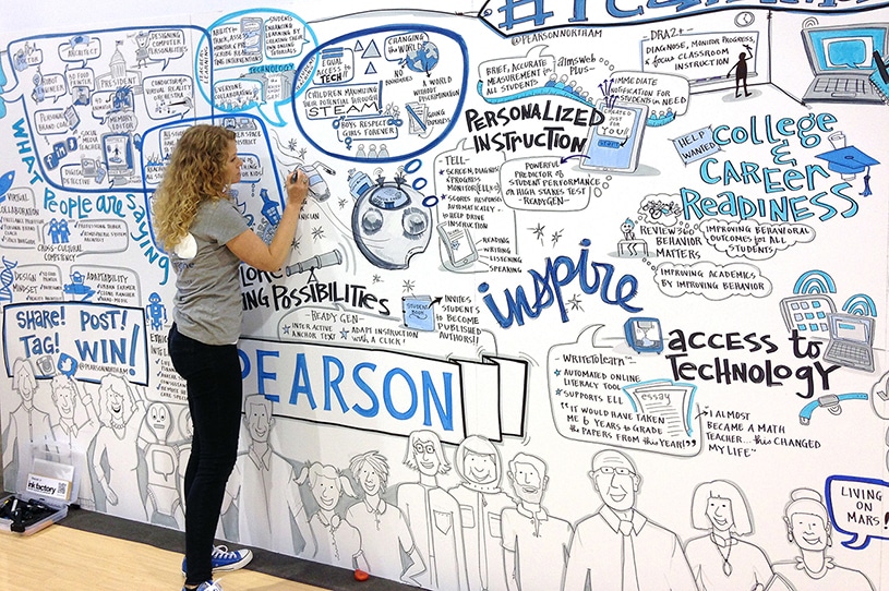 An artist from Ink Factory draws live on a trade show booth for Pearson