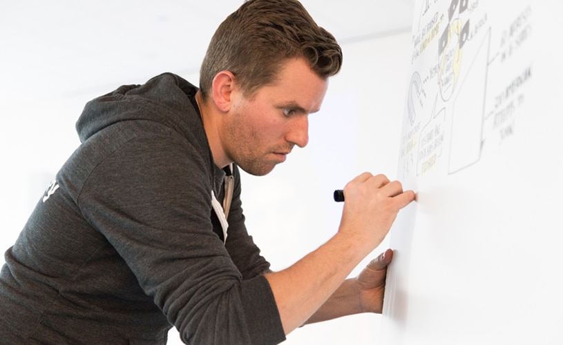 An artist uses his pinky to stabilize while writing on a vertical surface