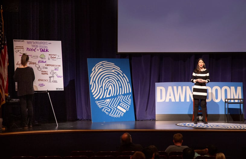 Ink Factory artist draws net to a speaker on stage during a speech