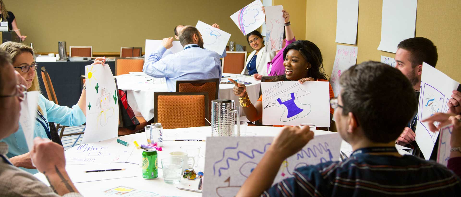 Participants holding up their collaborative drawings while learning how to take visual notes