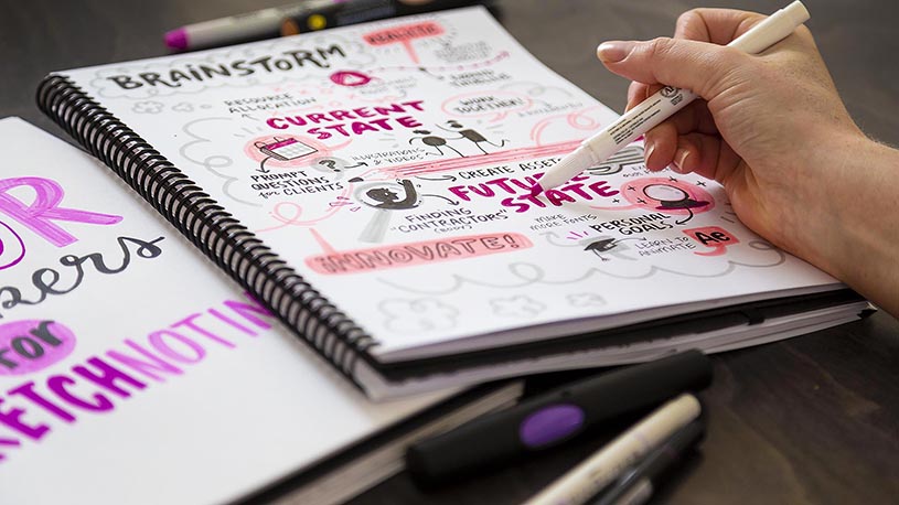 An artist colors visual notes in a sketchbook